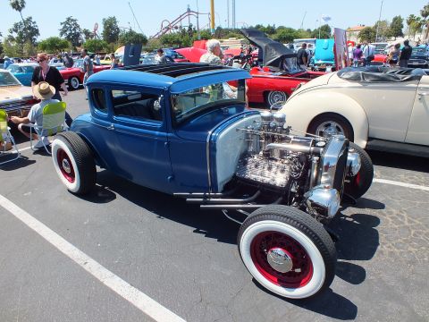 Blue chopped Ford coupe hot rod with chrome flathead V8 and whitewall tires at car show