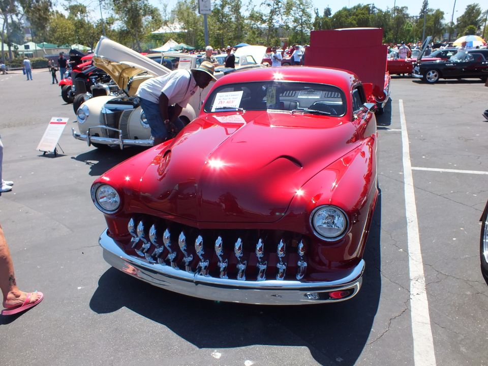 Red chopped Mercury-style custom coupe with toothy chrome grille front view at car show