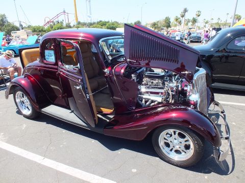 Maroon 1933-34 Ford five-window coupe with open hood and chrome engine at car show