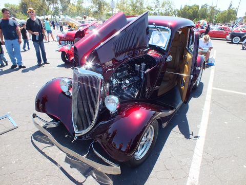 Maroon 1934 Ford coupe hot rod with open hood and tan interior at outdoor car show