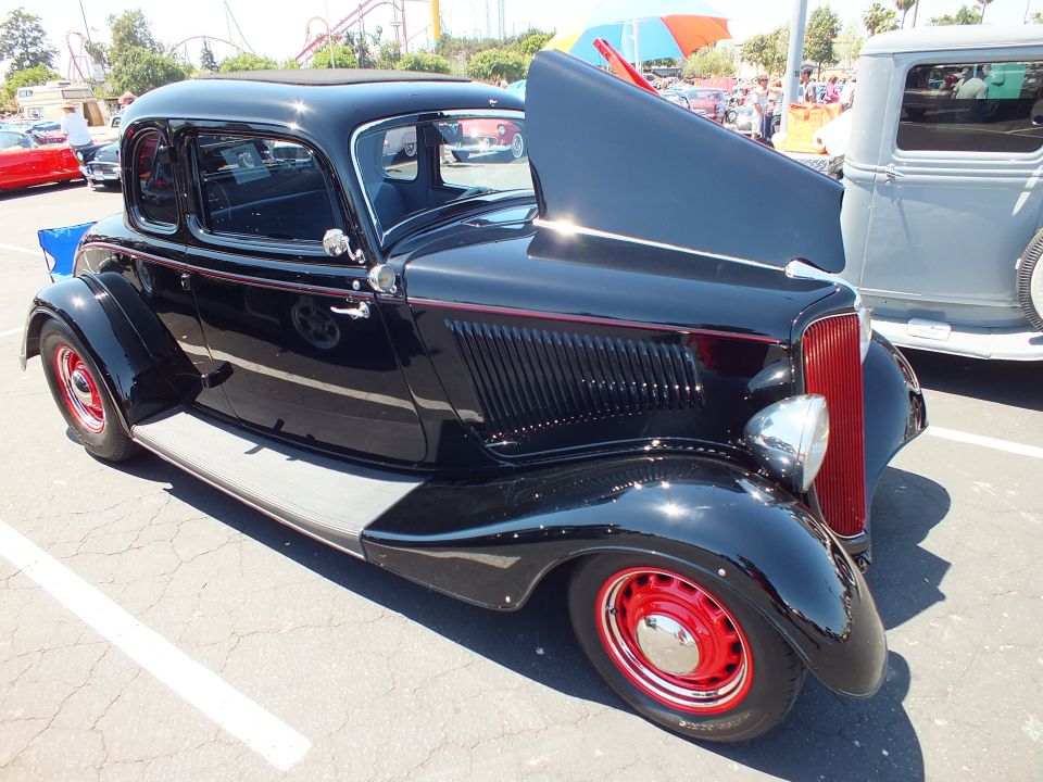 Black 1933-34 Ford five-window coupe with red wheels and open hood at car show