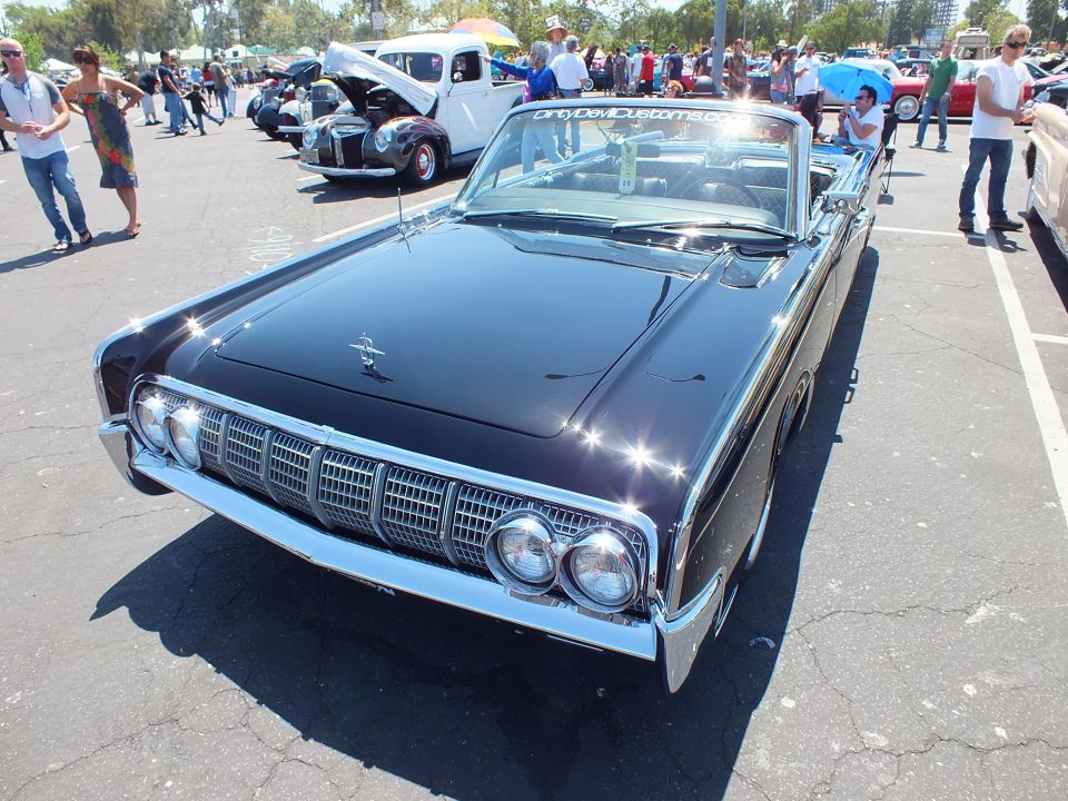 Front view of dark 1960s Lincoln Continental convertible with quad headlights at car show