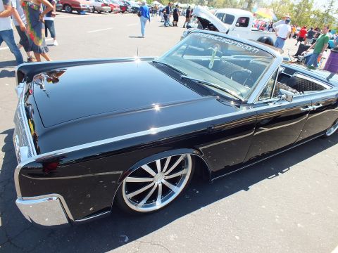 Rear quarter of lowered black Lincoln Continental convertible on chrome wheels at car show