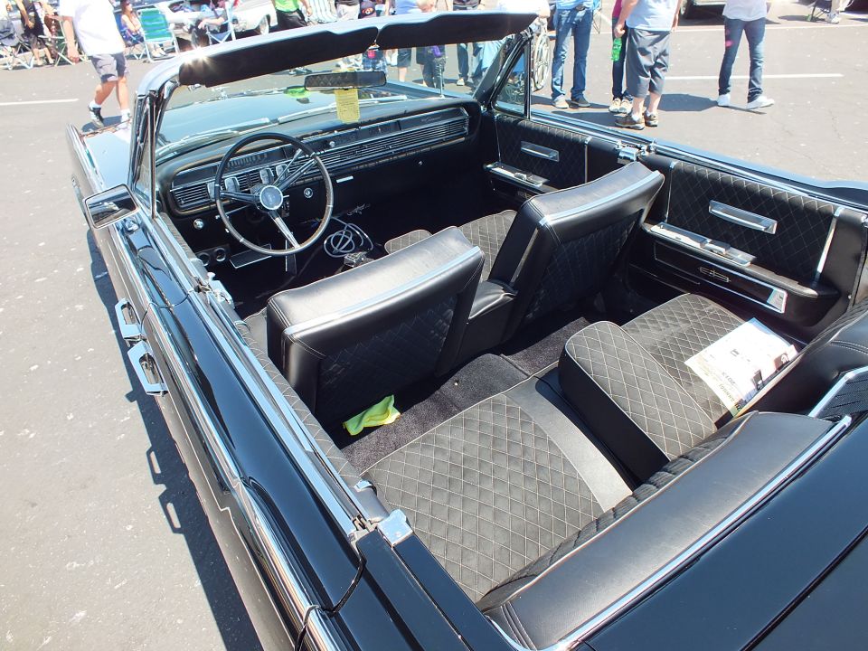 Black diamond-tufted leather interior of 1960s Lincoln convertible with steering wheel