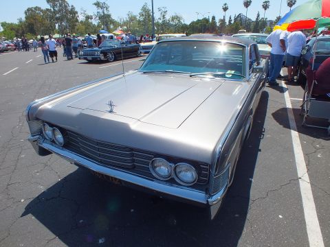 Front of silver 1960s Lincoln Continental sedan with chrome grille and quad headlights