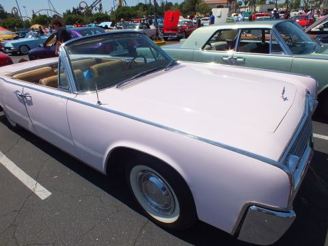 Pink 1960s Lincoln Continental convertible with tan interior at car show