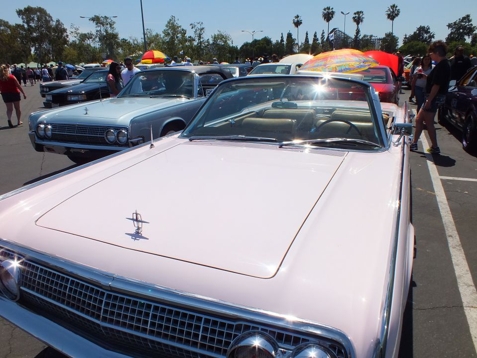 Hood and grille of pink 1960s Lincoln convertible with hood ornament at car show