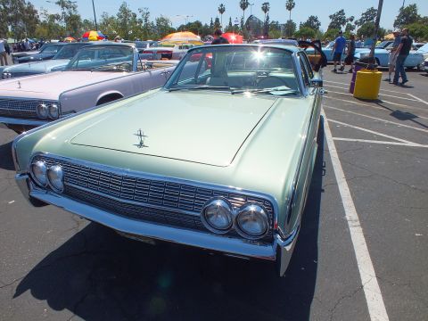 Front of light green 1960s Lincoln Continental sedan with chrome grille and hood ornament