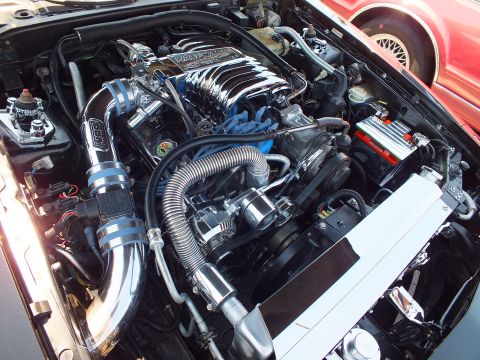 Chromed V8 engine bay with polished intake manifold and braided lines in a coupe