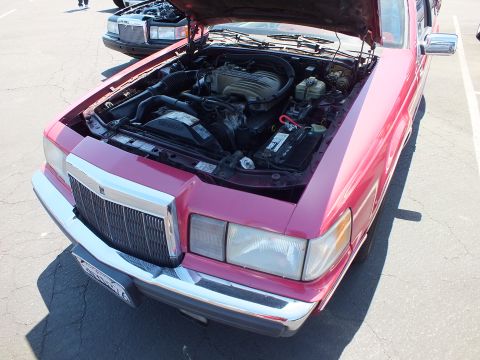 Front of red Lincoln coupe with hood open showing engine, chrome grille and quad headlights