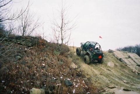 1992 Ford Bronco - An off-road buggy navigates a steep, rocky incline under an overcast sky.