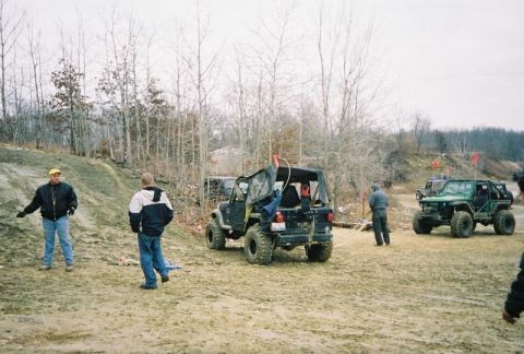 1992 Ford Bronco - Modified Jeeps are seen on a dirt track during an off-road event, with several individuals observing the vehicles.