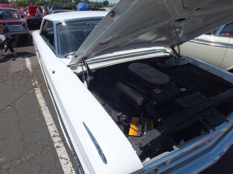 White classic car with hood open showing large V8 engine and air cleaner