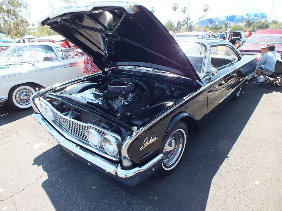 Black 1960 Ford Starliner with hood open and chrome trim at car show