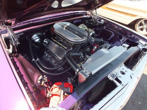 Chromed V8 engine with finned valve covers in purple car engine bay