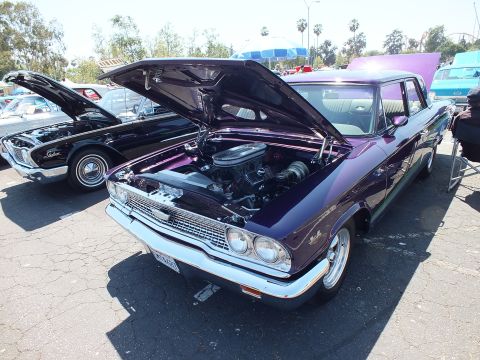 Purple custom 1960s Ford with hood up beside black Ford at car show