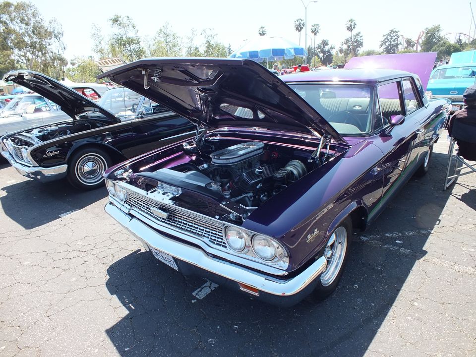 Purple custom 1960s Ford with hood up beside black Ford at car show