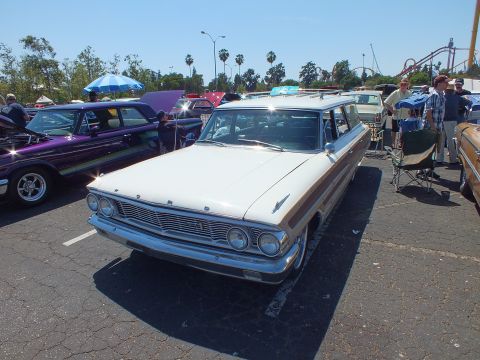 White and woodgrain 1964 Ford station wagon with roof rack at car show