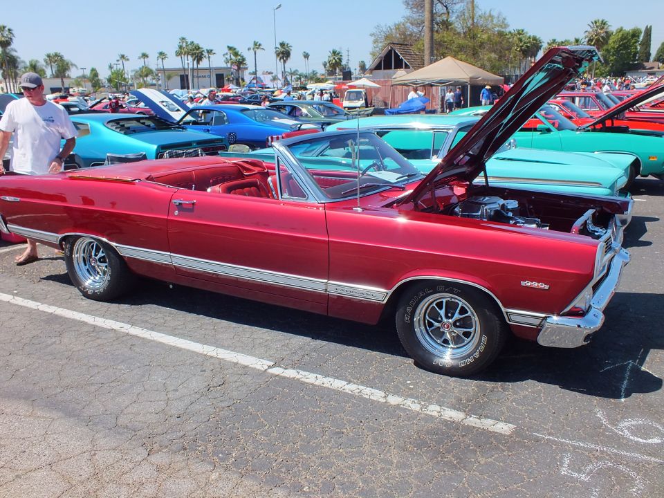 Dark red Ford Fairlane convertible with hood up at outdoor car show