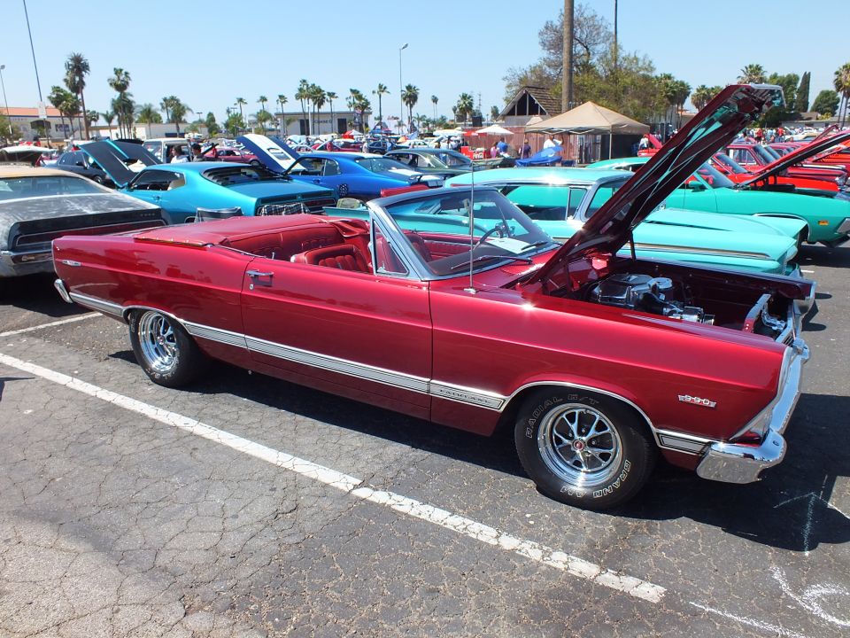 Dark red Ford Fairlane GT convertible side view with hood up at show