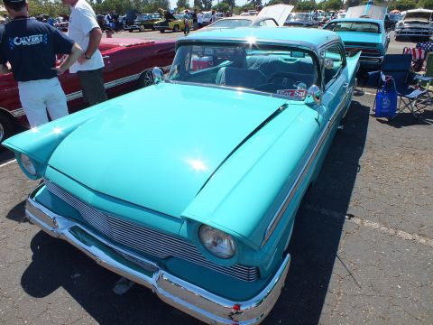 Turquoise late-1950s sedan with chrome grille parked at car show