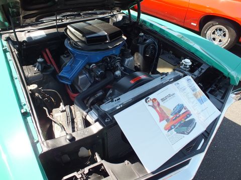 Engine bay of classic muscle car with blue intake and chrome air cleaner