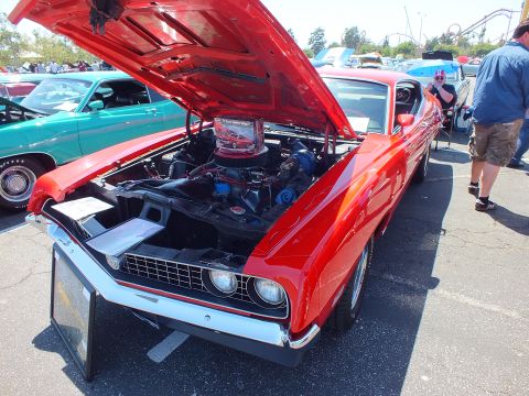 Red Ford Torino with open hood showing chrome air cleaner at car show