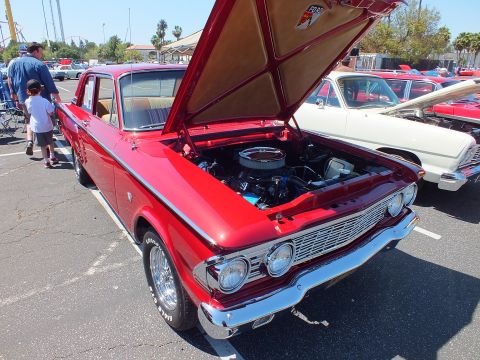 Red early-1960s Ford sedan with open hood at car show