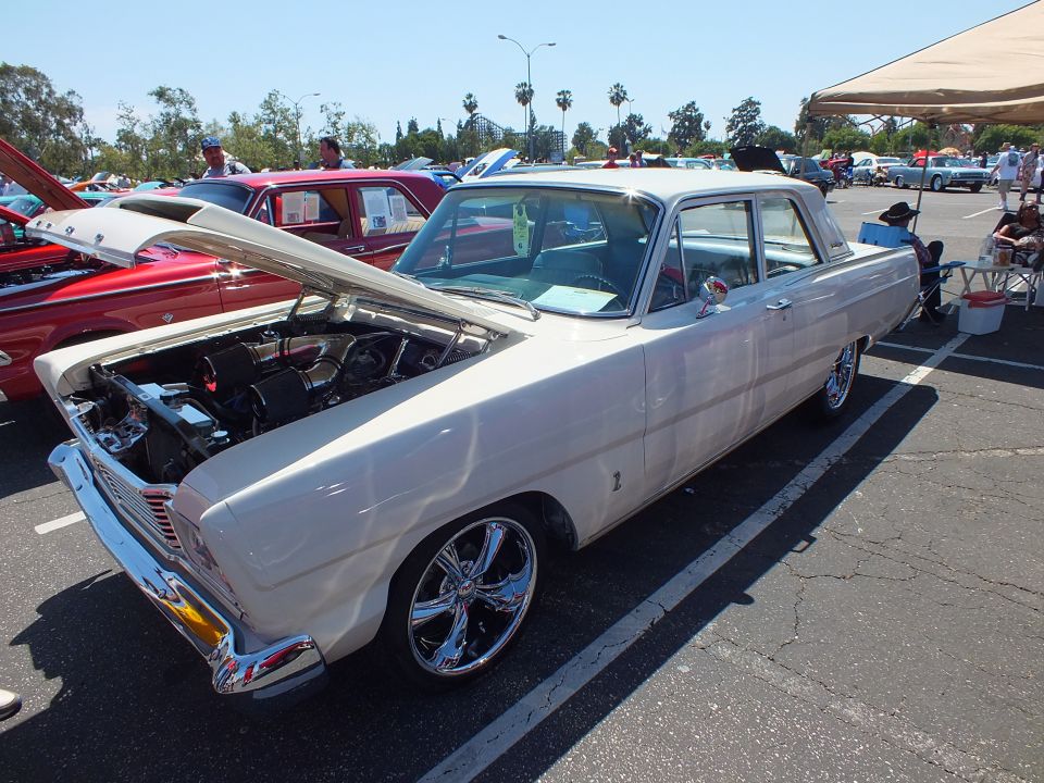 White classic two-door sedan with chrome wheels at outdoor car show