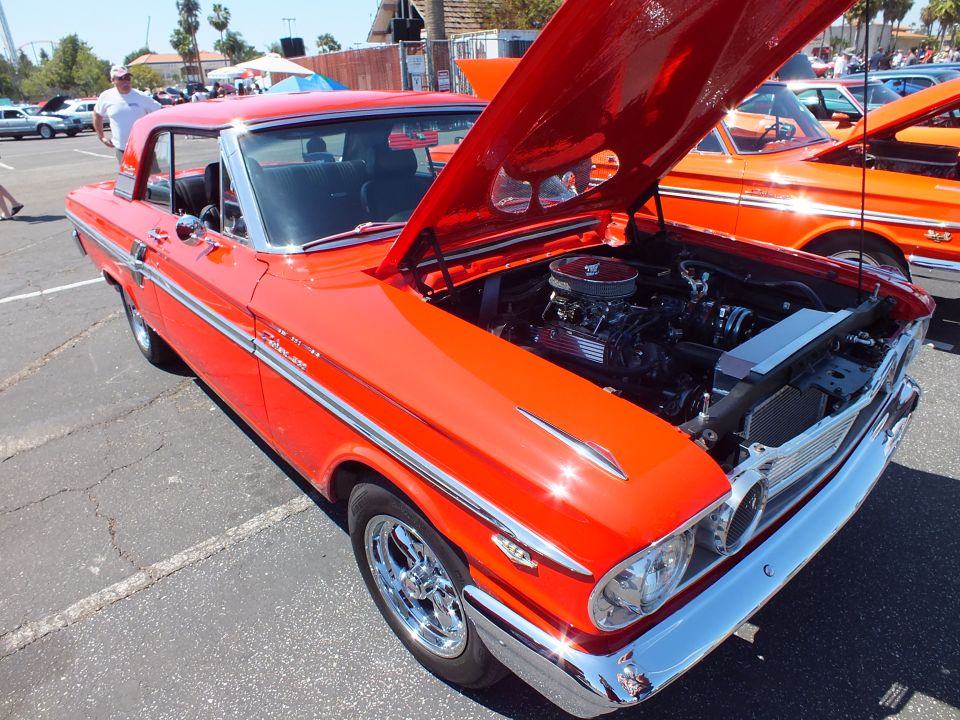 Orange Ford Fairlane Thunderbolt-style hardtop with open hood at car show