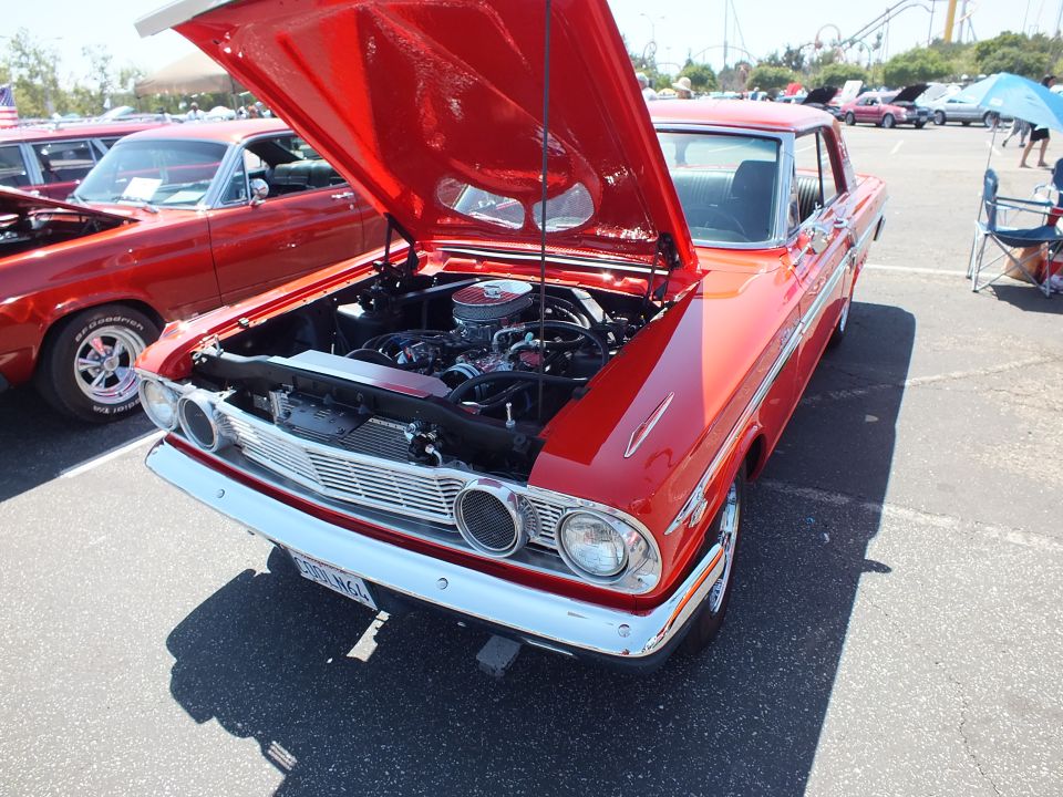 Red Ford Fairlane with open hood, chrome grille and California plate