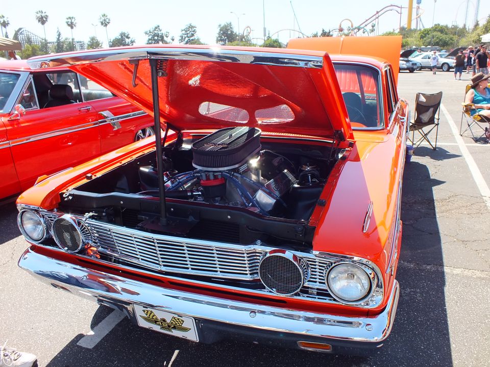Orange Ford Fairlane with open hood showing chrome air cleaner at car show