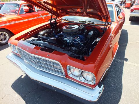 Copper-orange Ford Torino with open hood and FORD grille at car show
