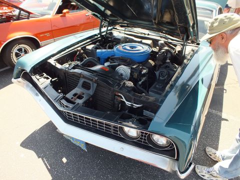Teal classic Ford with open hood showing V8 engine with blue air cleaner at a car show