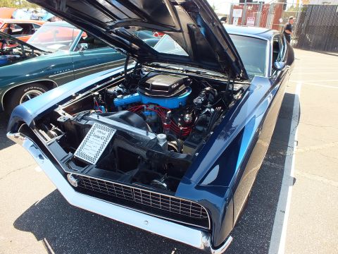 Dark blue classic coupe with open hood showing blue V8 engine and chrome valve covers