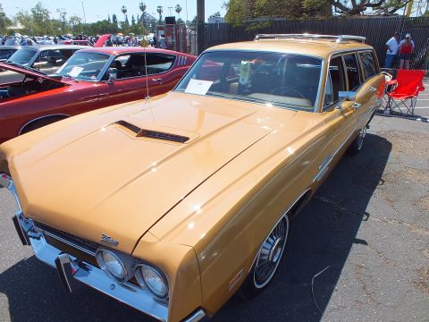 Gold station wagon with hood scoop, roof rack and dual headlights at car show