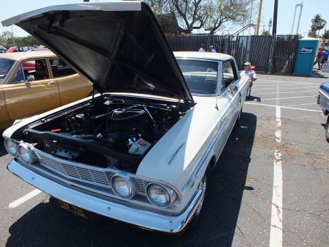 White and blue two-door classic with open hood showing engine, front quarter view