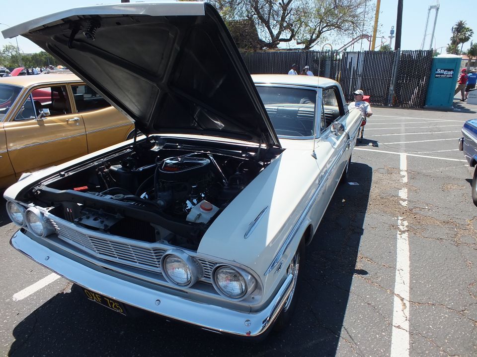 White and blue two-door classic with open hood showing engine, front quarter view