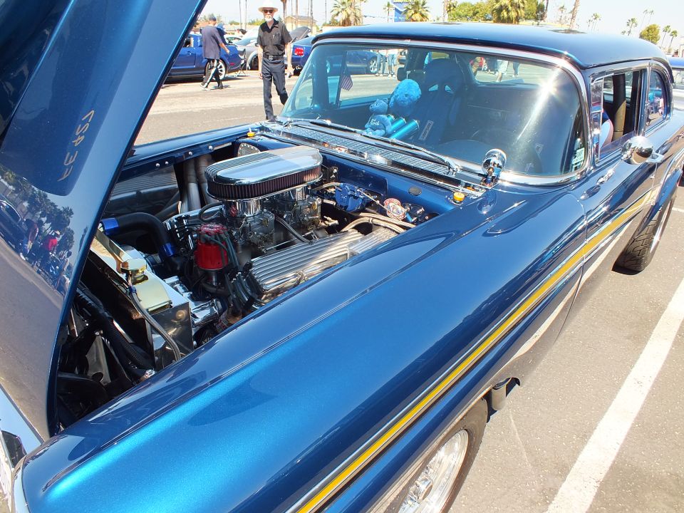 Blue 1950s custom car with gold stripe and open hood showing chrome V8 engine