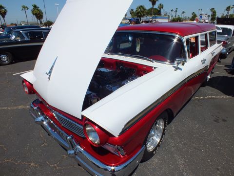 Red and white 1950s station wagon with open white hood and chrome wheels