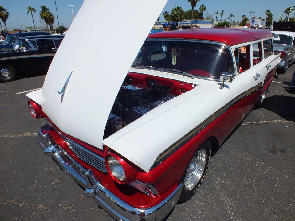 Red and white 1950s station wagon with open white hood and chrome wheels