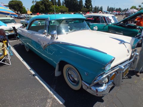 Turquoise and white 1950s hardtop with whitewall tires and V-emblem at car show