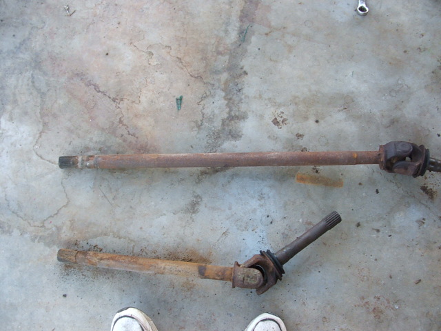 two rusty driveshafts on concrete floor