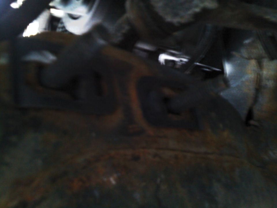 Undercarriage view of rusty metal parts and suspension components