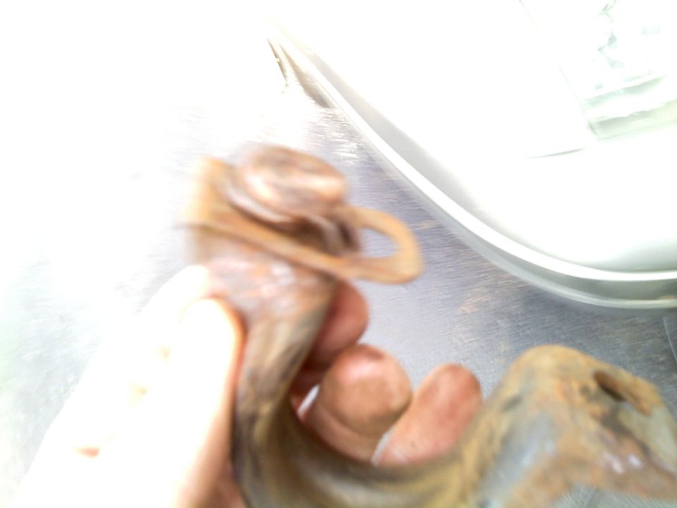 Rusty metal part held in hand, possibly a swaybar bushing
