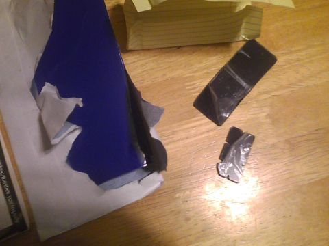 2003 Ford Crown Victoria - A car emblem and torn blue material are on a wooden table.