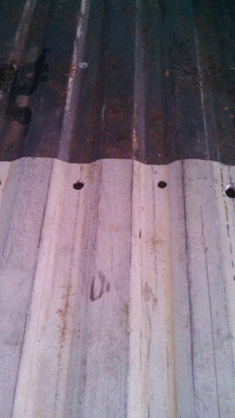 1979 Ford Bronco - Close-up of a weathered, corrugated metal surface, possibly a truck bedliner, showing signs of rust and drill holes.