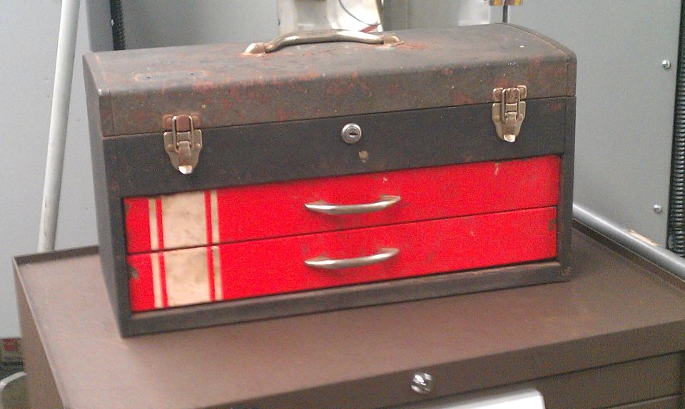 Metal toolbox with two red drawers and silver handles. White and red stripes on the left side of the drawers