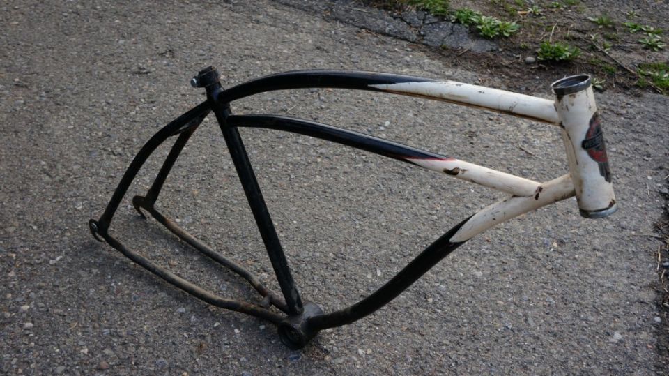 bicycle frame with black and white paint, resting on asphalt