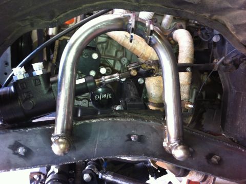 1987 Suzuki Samurai - Custom suspension parts are installed on a vehicle, showing engine and exhaust details.